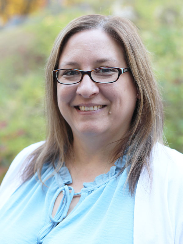 Marcia Chapman - woman wearing glasses with light brown hair wearing a blue top