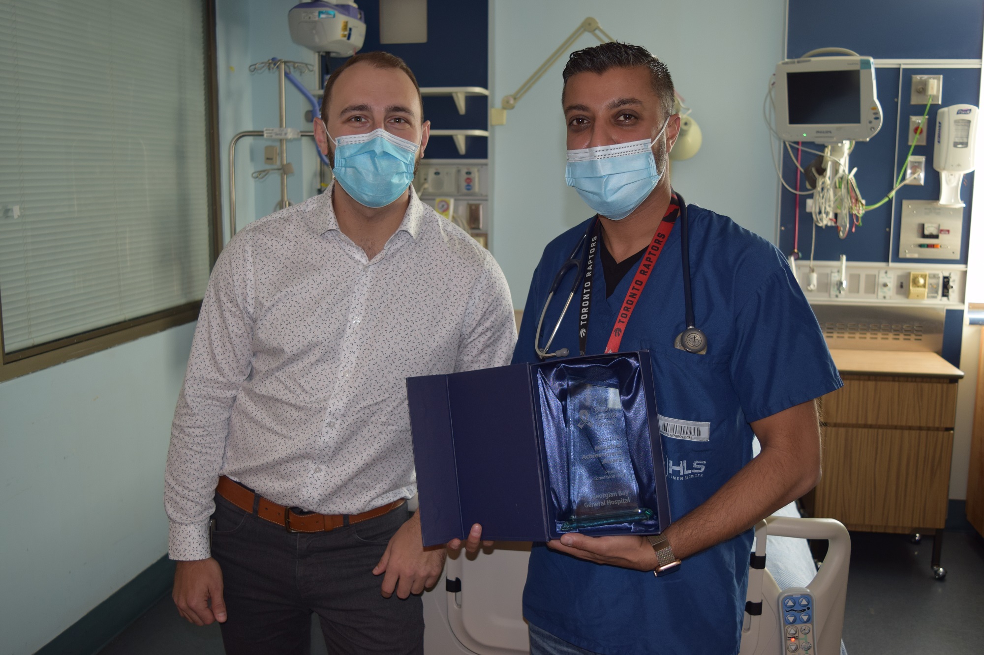 Dr. Tahir and Tyler Pilon. The doctor is holding a box with a certificate in it.