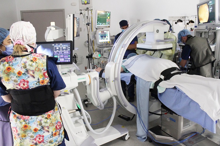 A group of medical staff in an operating room with a large piece of specialized machinery