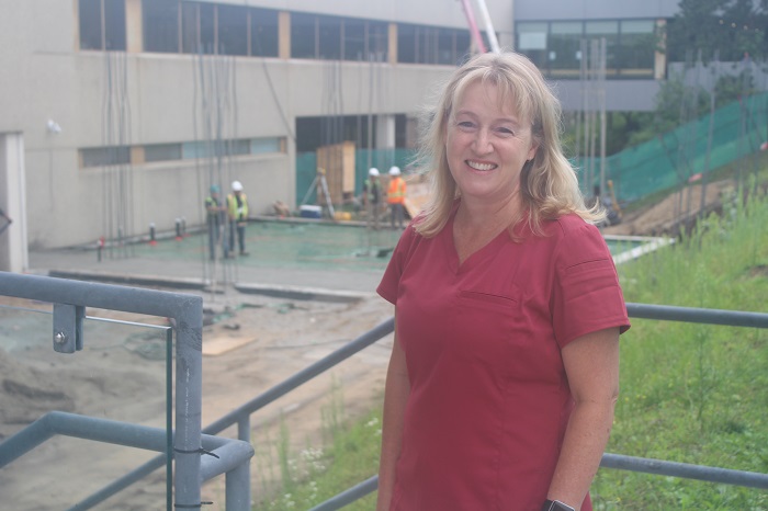 Woman in healthcare scrubs overlooks construction site