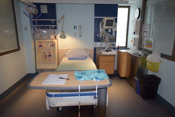ICU room with a bed, tray, sink, and all the necessary equipment hanging on the wall.