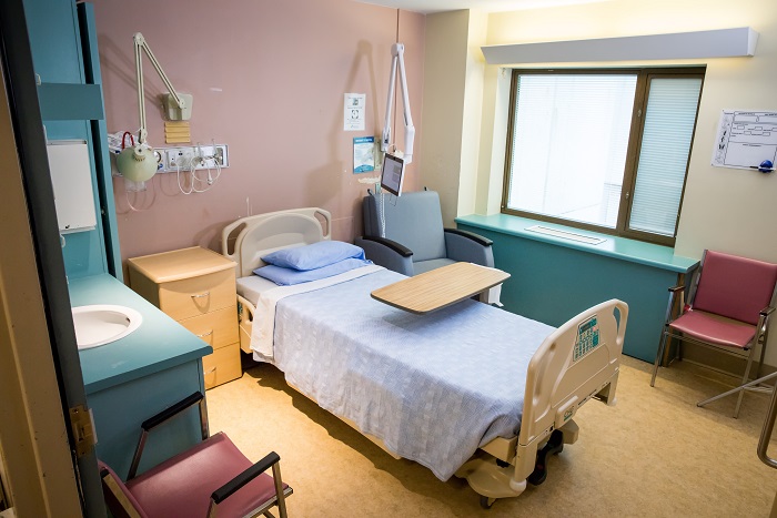 A hospital room showing a bed, side table, tray and view out the window