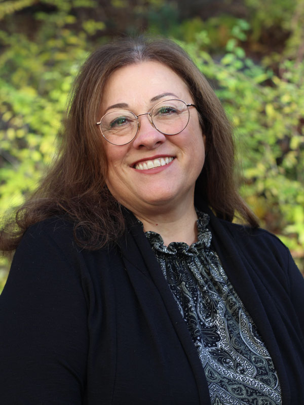 Karen Redpath - a woman with medium black hair wearing round glasses and a black top
