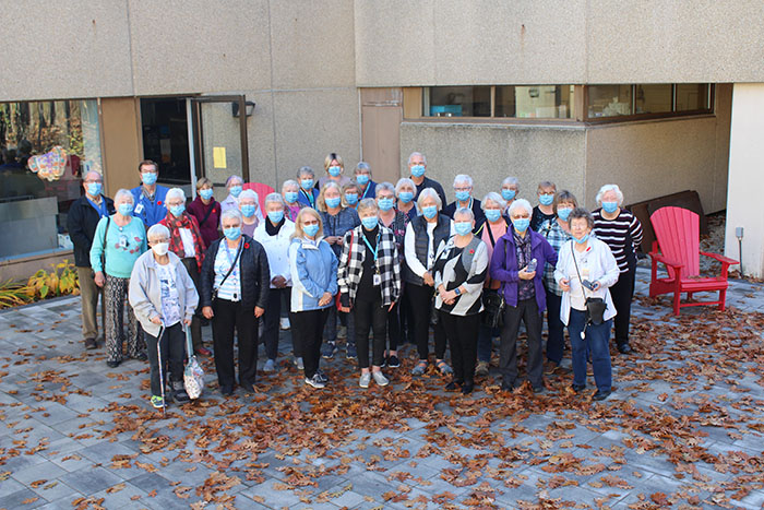 Over 30 volunteers wearing masks posing outside of the hospital on a fall day.
