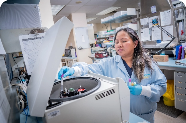 A female hospital worker adds some test vials into a circular machine